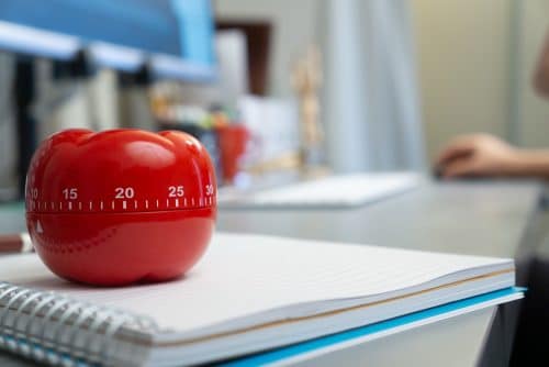 technique pomodoro - minuteur pomodoro en forme de tomate posé sur un bureau pour améliorer sa gestion du temps de travail