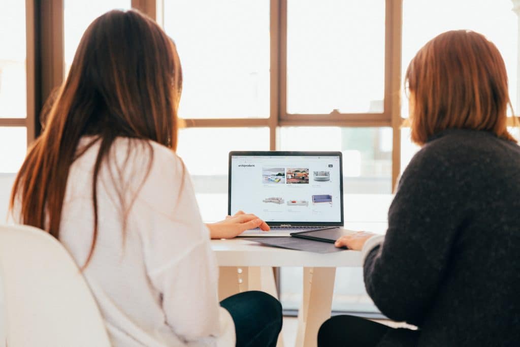 Deux femmes devant un ordinateur faisant le choix d'un CMS pour la création de leur site e-commerce