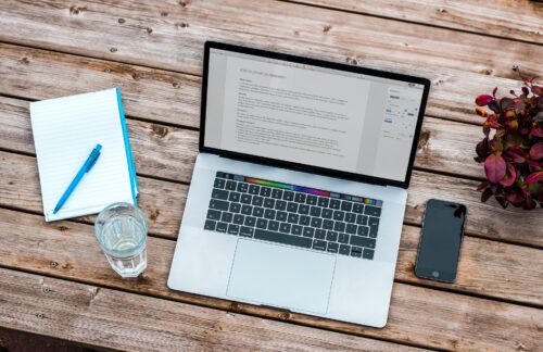 table où se trouvent un carnet d'écriture et un ordinateur d'une personne qui va écrire un article pour du guest blogging