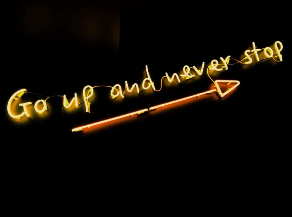 Mantra de business en néon où il est inscrit "go up and never stop" signifiant "va de l'avant et n'arrête jamais".